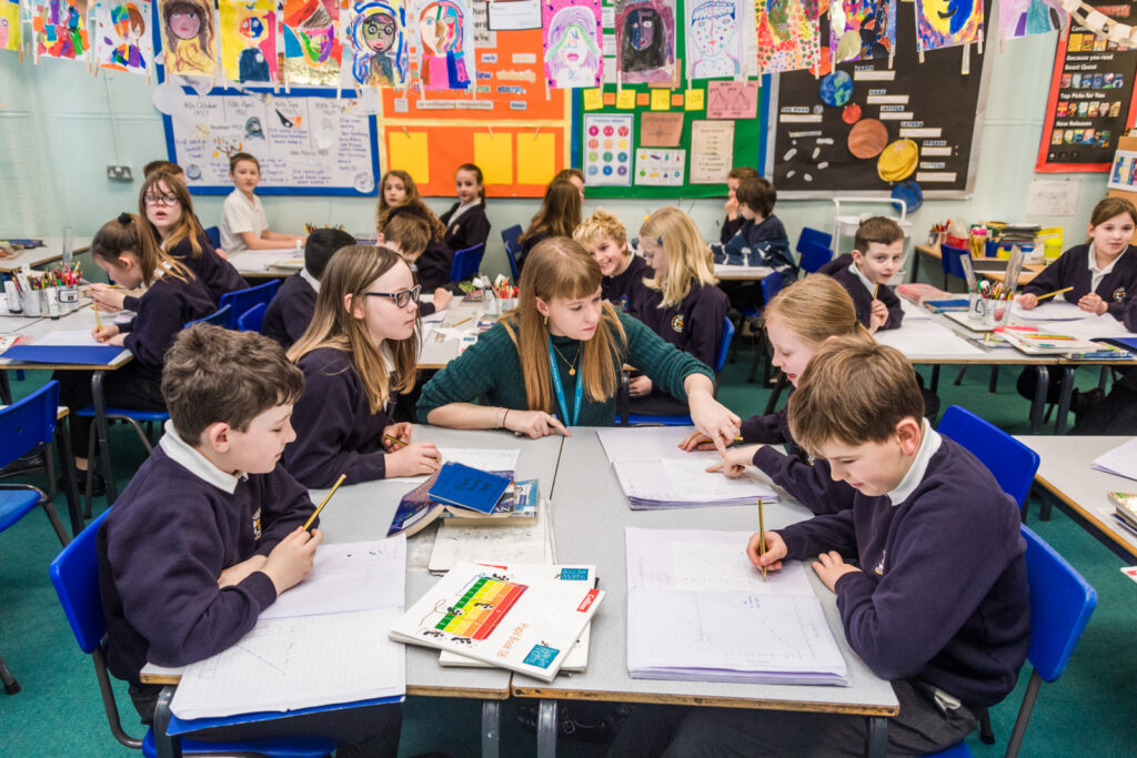 teacher helping the students with their work in the classroom