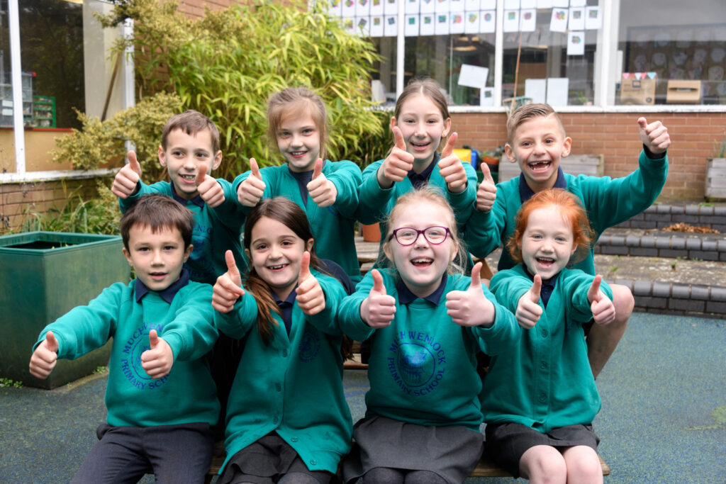 a group of students with their thumbs up smiling