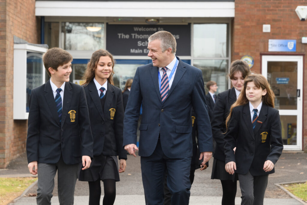 a picture of a teacher with four students walking