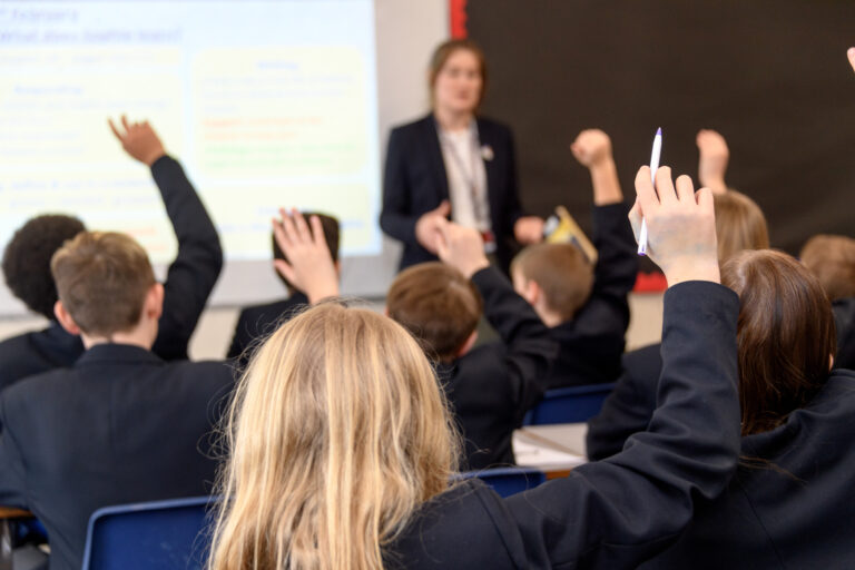 a picture of students with their hands up waiting to answer a question