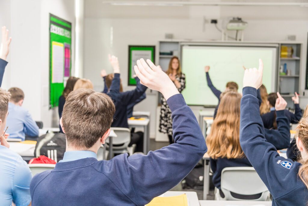 a picture of a class with their hands up waiting to answer a question