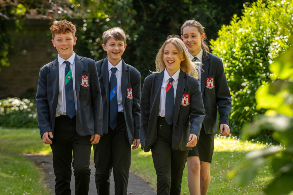 four students walking outside laughing and smiling