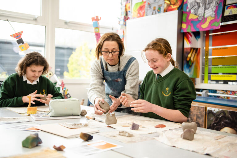 teacher helping the student with her clay work